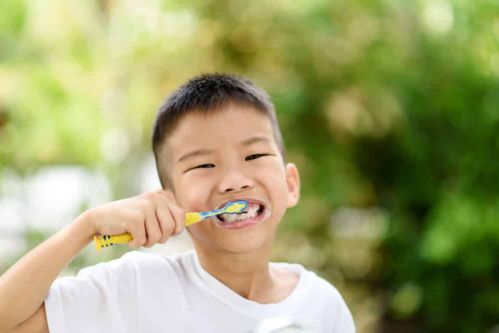 Smiling child brushing teeth outdoors – promoting good oral hygiene habits with guidance from Pinnacle Pediatric Dentistry Houston