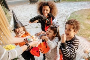 Children in Halloween costumes trick or treating and eating candy.